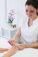 Manicurist filing woman's nails