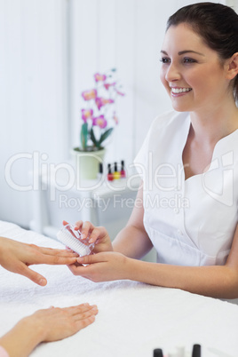 manicurist using nail brush on woman's nails