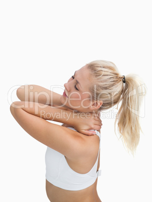 Side view of sporty young woman massaging neck