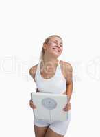 Excited young happy woman holding weighing scales