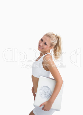 Portrait of young happy woman holding out weighing scales