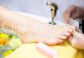 Close-up of nail technician filing woman's toe nails