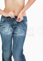 Midsection of slim woman buttoning jeans
