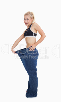 Young healthy woman wearing old pants after losing weight