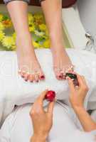 Woman applying nail varnish to toe nails at spa center