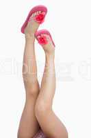 Female legs wearing pink daisy flip-flops