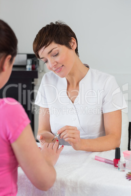 Nail technician applying nail varnish to finger nails