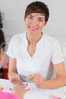 Portrait of woman applying nail varnish to finger nails