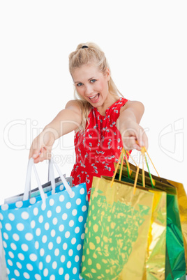 Cute excited young woman holding out shopping bags