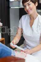 Nail technician filing woman's toe nails