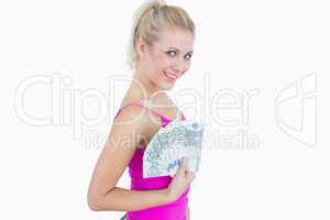 Portrait of happy young woman holding fanned euro banknotes