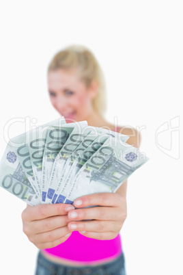 Young woman holding out fanned euro banknotes