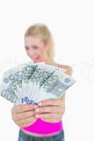 Young woman holding out fanned euro banknotes