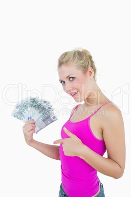 Portrait of happy woman pointing at fanned euro banknotes