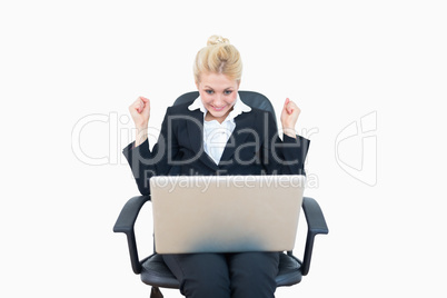 Successful business woman clenching fists in victory with laptop