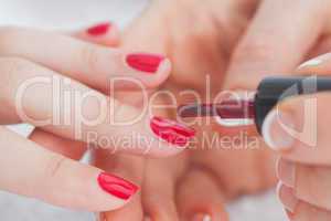 Details shot of hands applying red nail varnish to nails