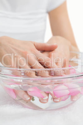 Woman's hands in bowl with petals at hands spa