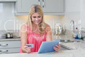 Woman doing online shopping on digital tablet in the kitchen