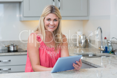 Portrait of casual woman using digital tablet in the kitchen