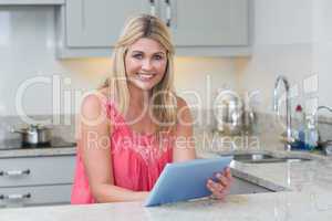Portrait of casual woman using digital tablet in the kitchen