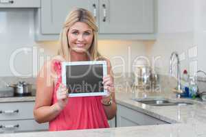 Portrait of casual woman holding digital tablet in kitchen