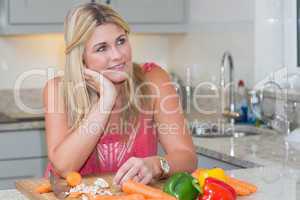 Thoughtful woman with vegetables in the kitchen