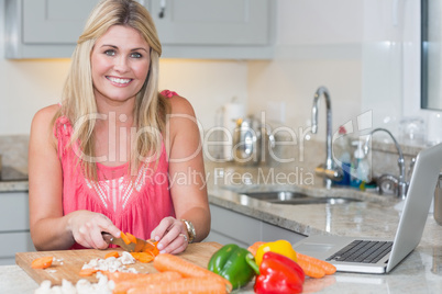 Portrait of woman making recipe from internet on laptop in kitch