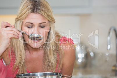 Young woman tasting food in kitchen