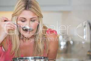 Young woman tasting food in kitchen