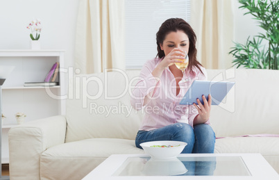 Woman drinking wine while using digital tablet at home