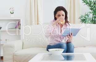 Woman drinking wine while using digital tablet at home