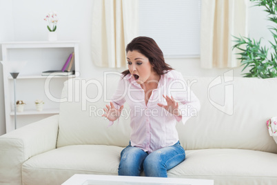 Shocked expressive woman sitting on couch