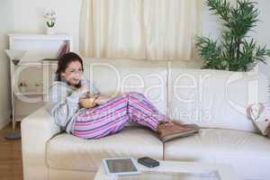 Happy woman on couch with bowl at home