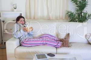 Scared woman throwing popcorn while watching film on couch