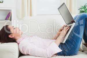 Casual woman lying on sofa and using laptop