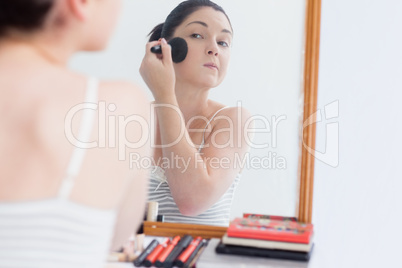 Young woman applying make-up on face