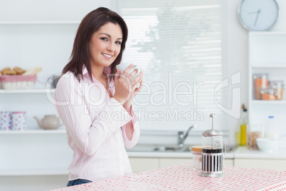 Smiling woman with cup of coffee in the kitchen