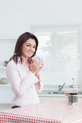 Smiling woman with cup of coffee in the kitchen