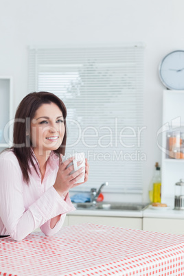 Happy woman looks away with coffee cup in hands