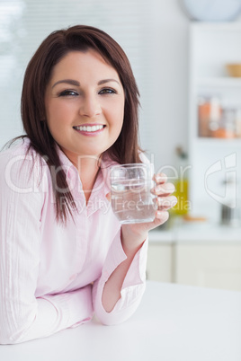 Young woman with glass of water in the kitchen