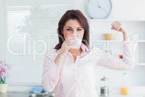 Woman drinking milk and flexing muscles