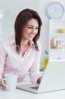 Happy woman with coffee cup using laptop