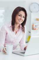 Portrait of woman with coffee cup and laptop