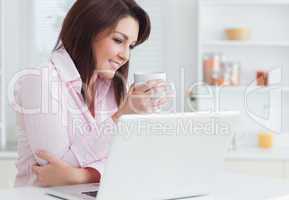 Smiling woman with coffee cup using laptop