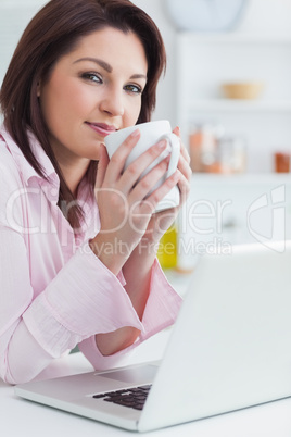 Portrait of woman with coffee cup and laptop