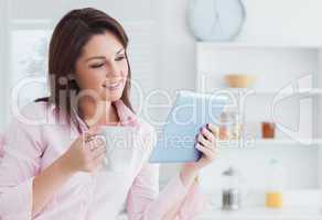 Smiling woman with coffee cup looking at digital tablet