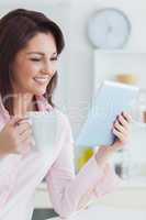 Smiling woman with coffee cup looking at digital tablet