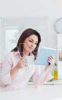 Woman with coffee cup looking at digital tablet