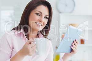 Close-up of smiling woman with coffee cup and digital tablet