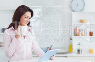 Woman with coffee cup looking at digital tablet